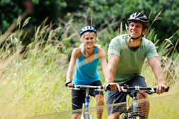 Young couple cycling through a meadow