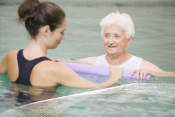 hydrotherapist treats elderly client in pool