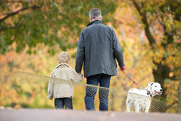 Father and son walk their dog through woodland park